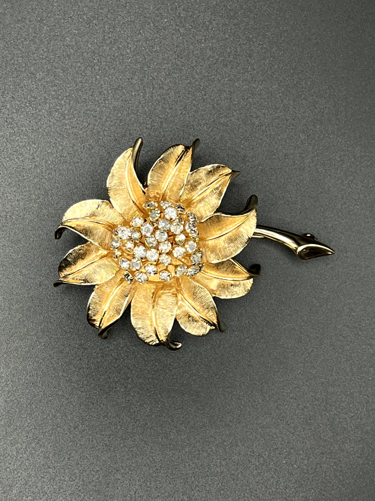 "Vintage gold-toned flower brooch pin showing clear rhinestone accent detail"